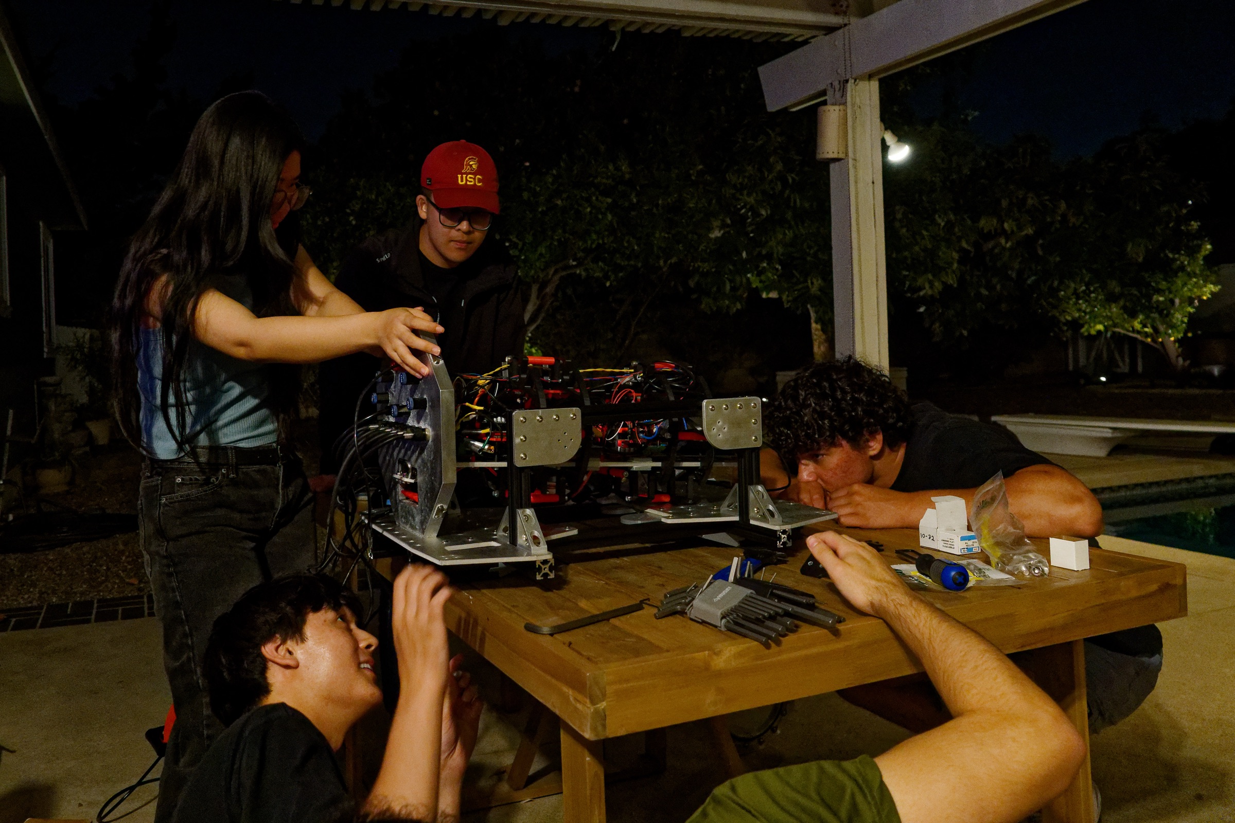 The team disassembling and rebuilding Barracuda late into the night beside the pool.