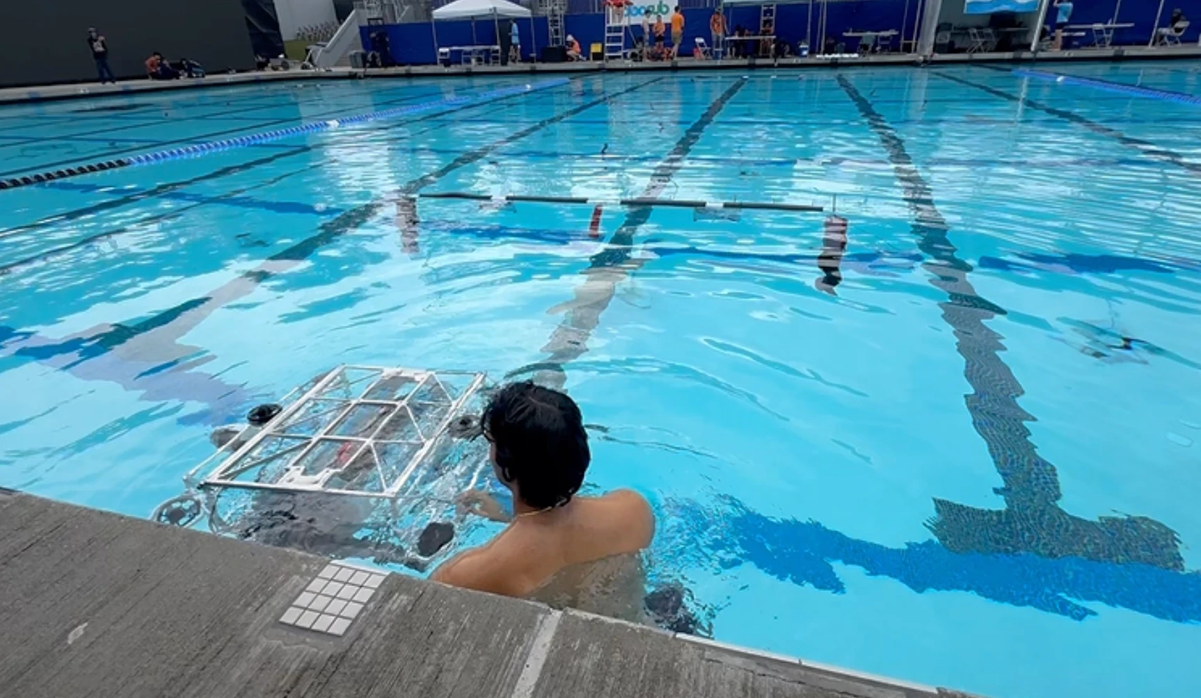 A team member in the competition pool guiding Barracuda toward the gate during a qualifying run at the Woollett Aquatics Center.
